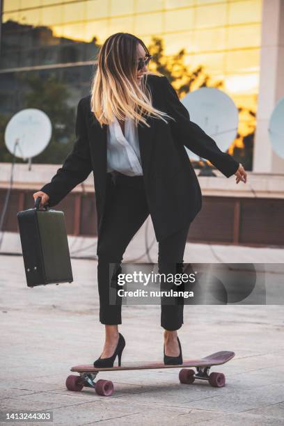 geschäftsfrau geht mit ihrem skateboard zur arbeit - woman longboard stock-fotos und bilder