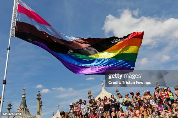 Festival goers watch a "progress" rainbow flag being waved at the Pride LGBTQ+ Community Parade – ‘Love, Protest & Unity’ during the Brighton Pride...