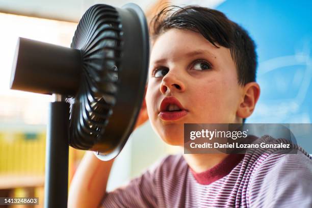 school boy using an electric fan as a radio microphone - climate change news stock-fotos und bilder