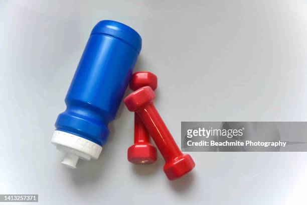 high angle view of a blue water bottle and a pair of red dumbbells on a table - exercise equipment stock pictures, royalty-free photos & images