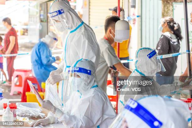 Medical workers work at a COVID-19 nucleic acid testing site as Sanya imposes city-wide static control to curb new COVID-19 outbreak on August 5,...
