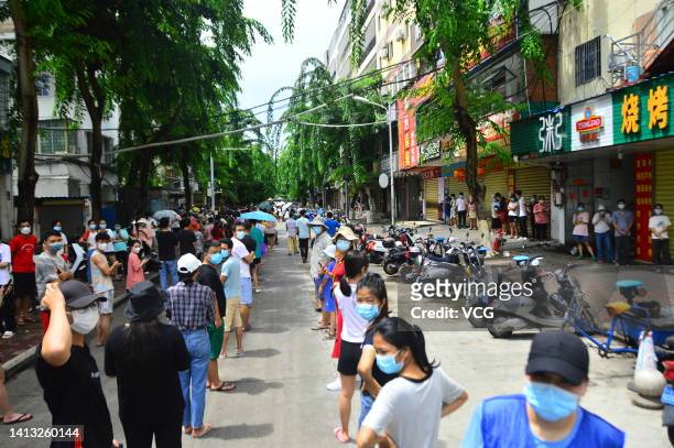 People line up for nucleic acid testing in the street as Sanya imposes city-wide static control to curb new COVID-19 outbreak on August 6, 2022 in...