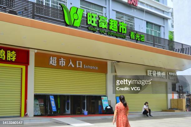 People walk by a closed supermarket as Sanya imposes city-wide static control to curb new COVID-19 outbreak on August 6, 2022 in Sanya, Hainan...