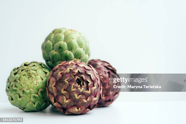 lots of purple and green artichokes on a white background. exotic vegetable. healthy food. farm harvest. dish ingredient. - cabbage flower stock pictures, royalty-free photos & images