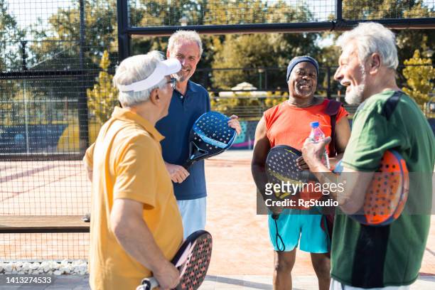 four senior friends enjoying together while playing padel - doubles sports stock pictures, royalty-free photos & images