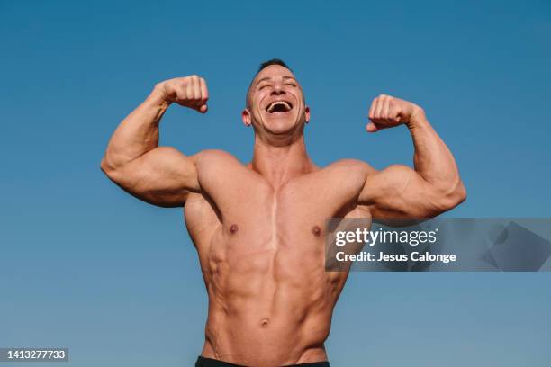 male bodybuilder with his arms in the air, smiling. men, bodybuilding, sport concept - forzudo fotografías e imágenes de stock