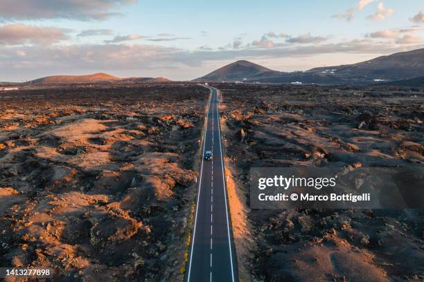 aerial view of straight road among volcanic landscape. lanzarote, spain - ランザローテ ストックフォトと画像