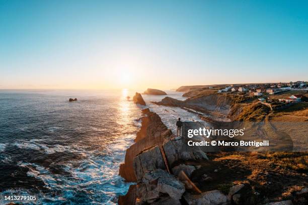 man standing on top of a cliff at arnia beach, spain - rock formation on beach stock pictures, royalty-free photos & images