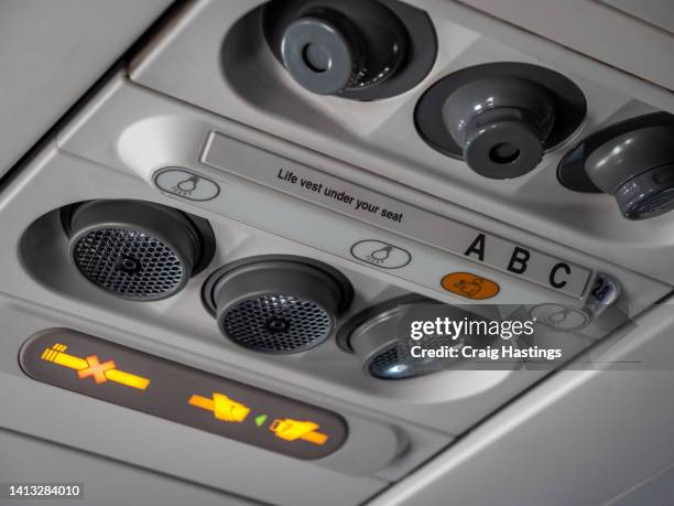 in flight light and fan central console with seat belt and no smoking sign above head. - airplane seats stock pictures, royalty-free photos & images