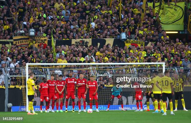General view as Marco Reus of Borussia Dortmund prepares to take a free kick as Edmond Tapsoba of Bayer Leverkusen is forced to become their team's...