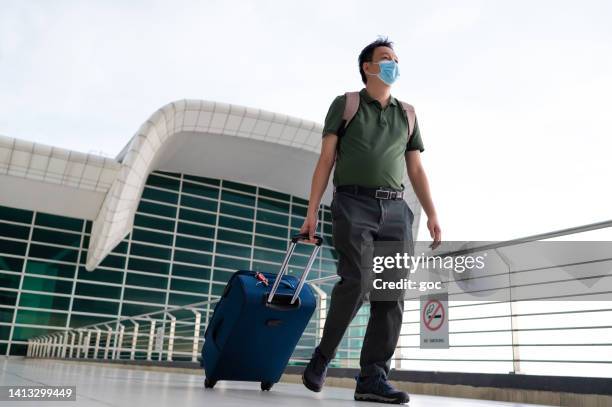 male tourist walking with luggage trolley in airport - kuala lumpur airport stock pictures, royalty-free photos & images