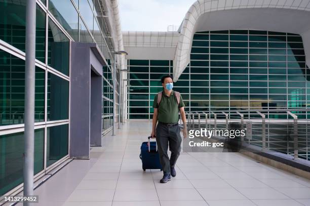 asian male tourist walking with luggage trolley in airport - kuala lumpur airport stock pictures, royalty-free photos & images