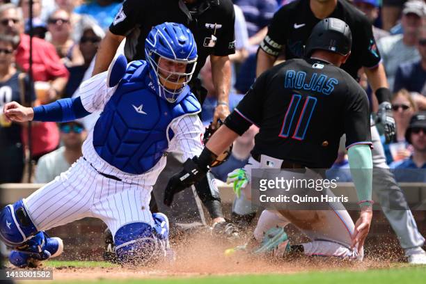 Higgins of the Chicago Cubs tags out Miguel Rojas of the Miami Marlins at home plate in the third inning at Wrigley Field on August 06, 2022 in...