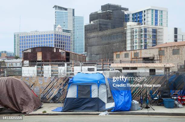 homeless encampment with skyscrapers in the background. - homelessness stock pictures, royalty-free photos & images