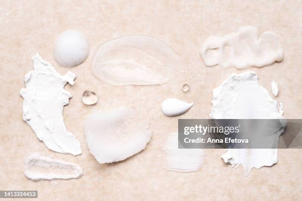 set of cosmetic smears applied on beige background. cleansing foam, lotions, scrubs, gels and moisturizing creams. beauty products with ceramides, polyglutamic acid and beneficial oils. flat lay style - facial cleanser stockfoto's en -beelden