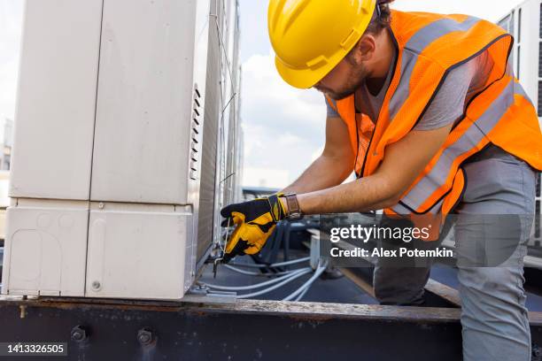 working on a rooftop to fix an air conditioner. - roof inspector stock pictures, royalty-free photos & images