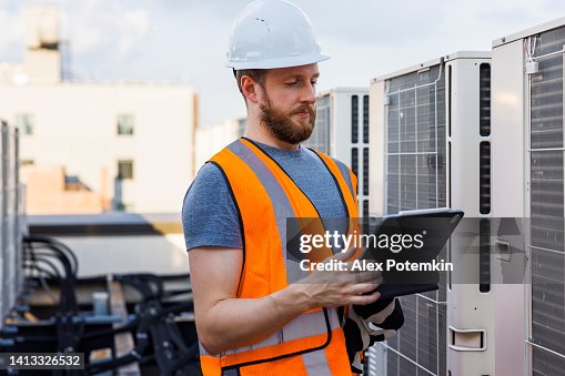 Using a portable computer, an engineer and technician check the air conditioning system. Using a portable computer, an engineer and technician check the air conditioning system.