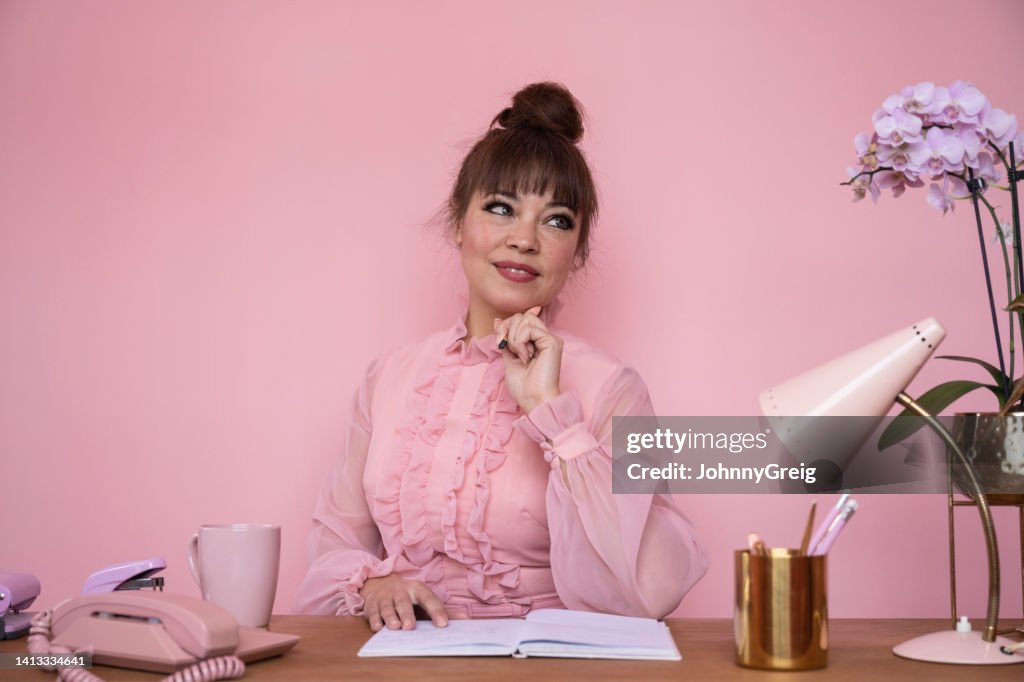 Portrait of businesswoman in ruffled blouse sitting at desk