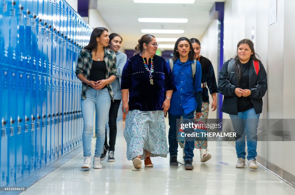 High school kids walking on a corridor alongside their teacher