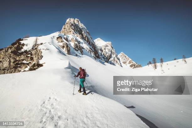 bergsteigerin beim wandern auf den verschneiten berg - schneeschuhwandern stock-fotos und bilder