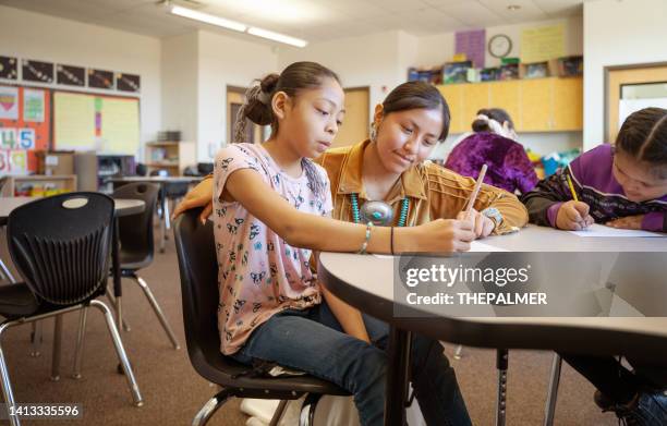 young indigenous navajo young teacher checking her students class work - victor ovies stock pictures, royalty-free photos & images