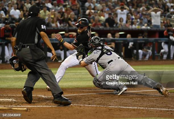 Seth Beer of the Arizona Diamondbacks is tagged out at home by Brian Serven of the Colorado Rockies during the fifth inning at Chase Field on August...