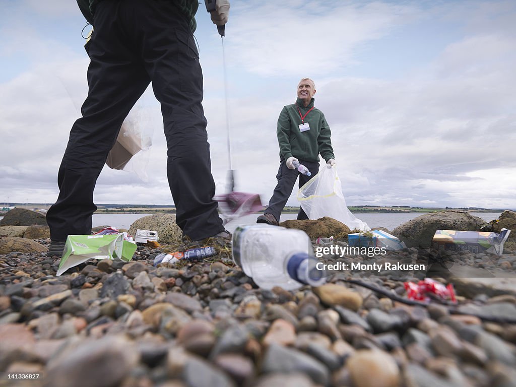 Two male environmentalists removing litter from seashore