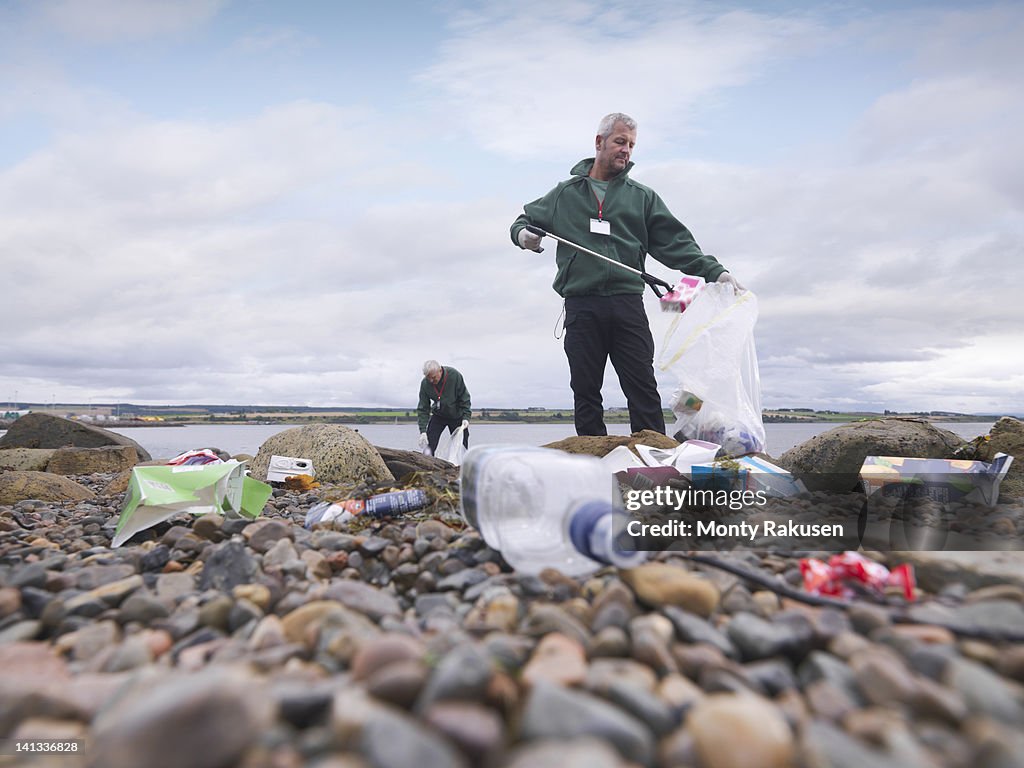 Two male environmentalists removing litter from seashore