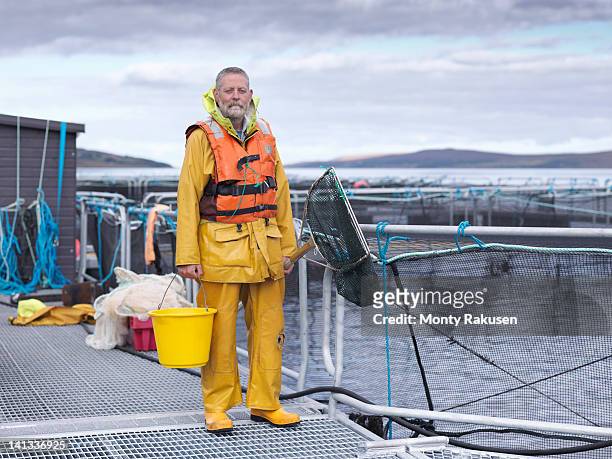 portrait of salmon farmer standing on pier of scottish salmon farm - aquaculture stock pictures, royalty-free photos & images