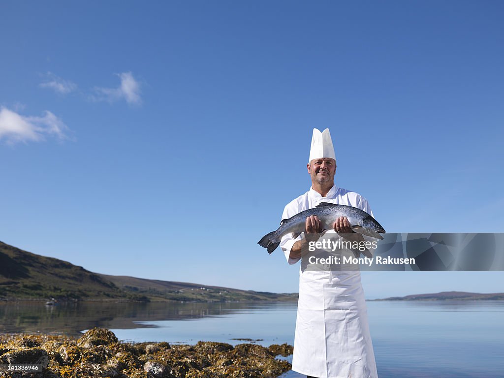 Portrait of chef holding freshly caught salmon by loch