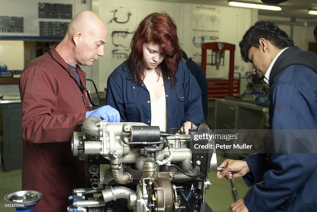 Profesor ayudando a estudiantes con motor de coche