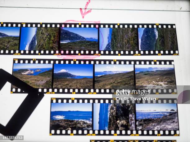 35mm transparency film strips on a lightbox with a slide mount. - geperforeerd stockfoto's en -beelden