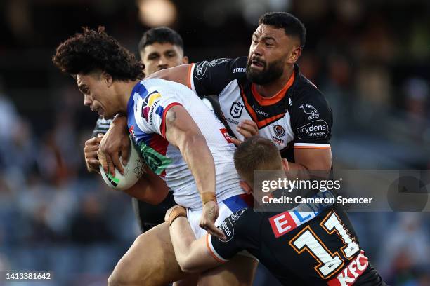 Pasami Saulo of the Knights is tackled during the round 21 NRL match between the Wests Tigers and the Newcastle Knights at Campbelltown Stadium, on...