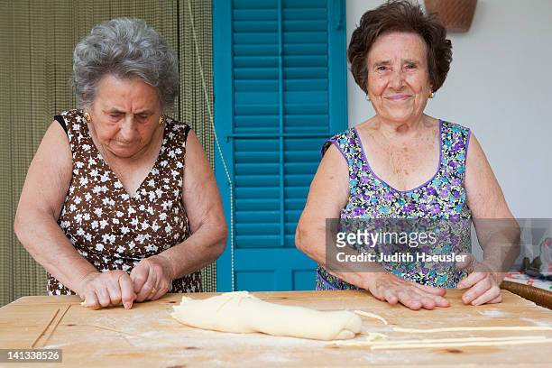 older women making pasta together - cultura italiana foto e immagini stock