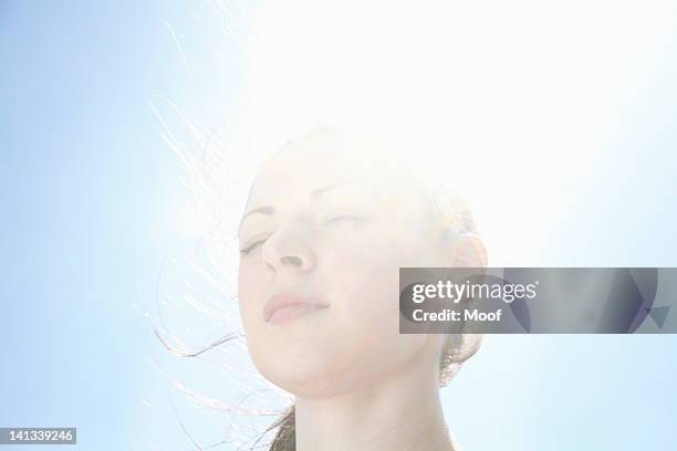 smiling womans face against blue sky - lighting technique stock pictures, royalty-free photos & images