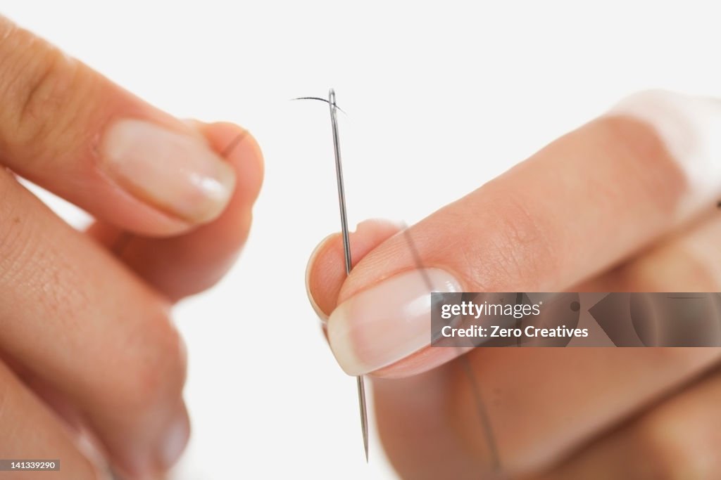 Close up of woman threading needle