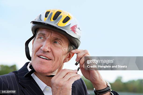 businessman putting on bicycle helmet - sports helmet stock pictures, royalty-free photos & images