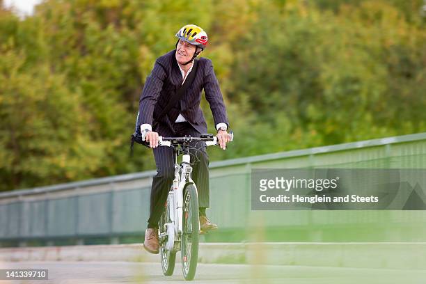 businessman riding bicycle on bridge - sports helmet stock pictures, royalty-free photos & images