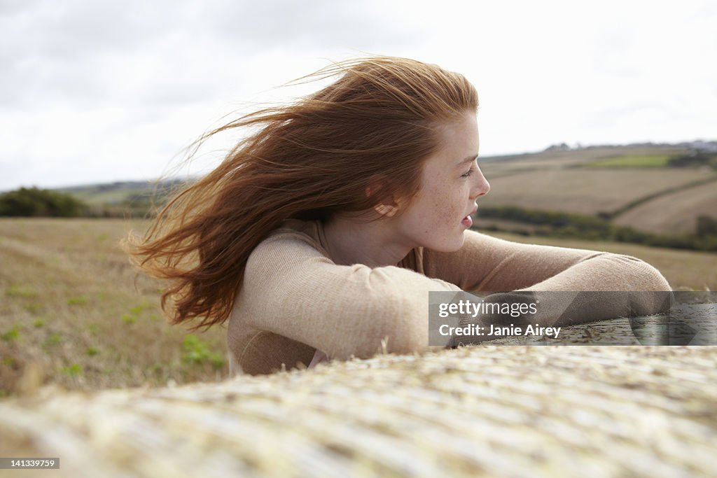 Teenage girl resting on haybale