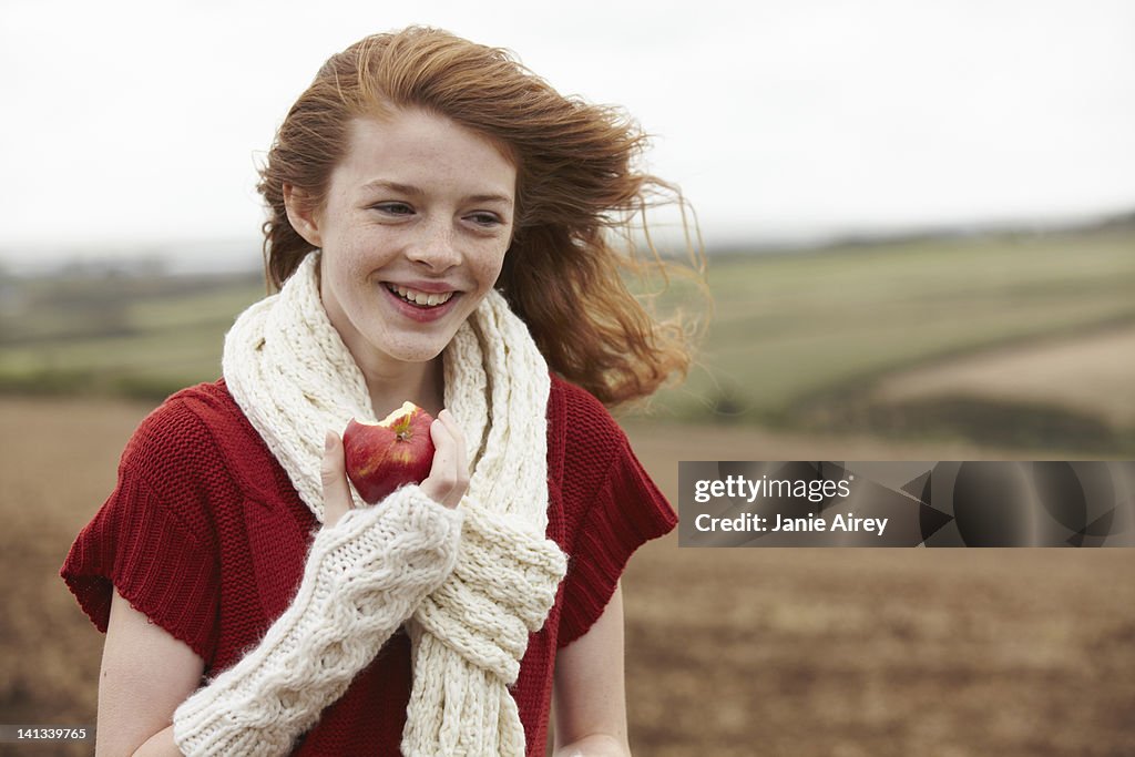 Teenage girl eating apple in field