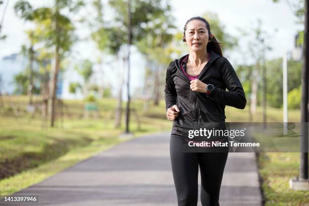 running for exercise "slows the aging process".  an asian woman running exercises in an urban park outdoors. - läufer dramatisch stock-fotos und bilder