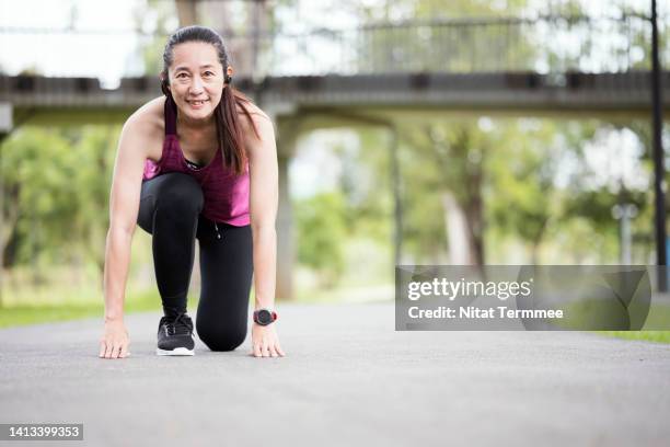 build power and speed by a sprint workout. an asian athletic female all set or starting to run down the street at a public park in city. - fitness or vitality or sport and women photos et images de collection