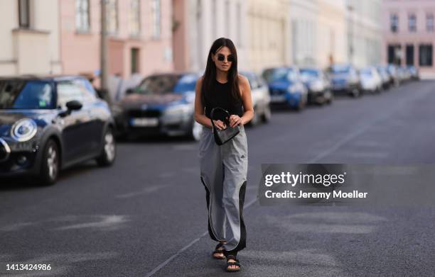 Anna Winter wearing Birkenstock black sandals, Holzweiler nylon grey black pants, Weekday black cropped top, by far black hobo mini bag and viu...