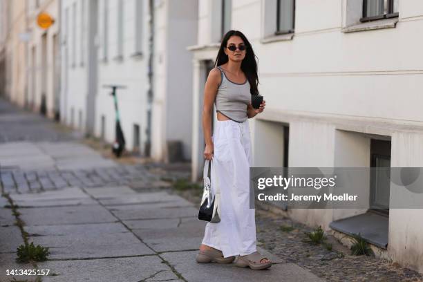 Anna Winter wearing Balenciaga x Crocs Pool Slide beige Sandal, Source Unknown white loose pants, Source Unknown silver shiny hobo bag, Balenciaga...