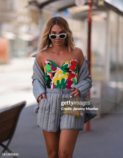 Karin Teigl wearing Holzweiler puffed grey shorts and matching grey jacket, Thierry Mugler colorful corset, Hermes mini Kelly leather yellow bag and...