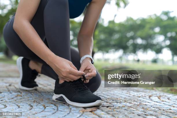 asian woman tying shoelaces get ready for a jog in the park. it's an exercise for good health. - exercise routine stock pictures, royalty-free photos & images