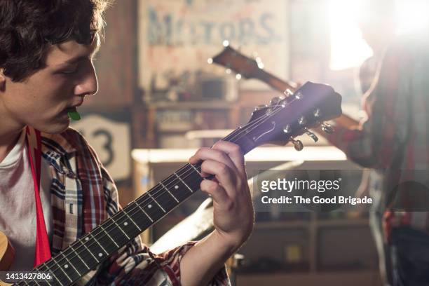 teenage boy practicing guitar in garage - boy band stockfoto's en -beelden