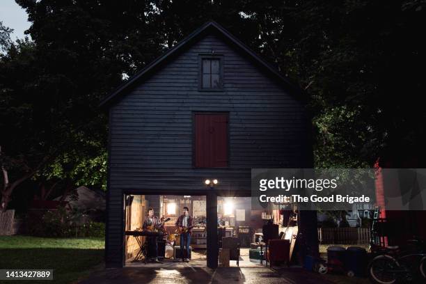 teenage boys rehearsing with band in garage at night - performance group stock pictures, royalty-free photos & images