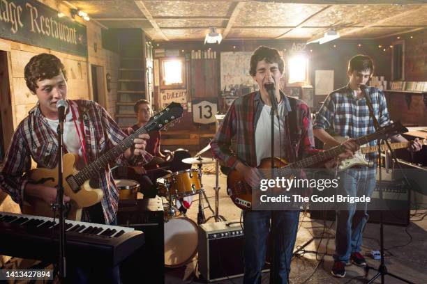 teenage friends singing and playing guitar during band practice in garage - bandprobe stock-fotos und bilder