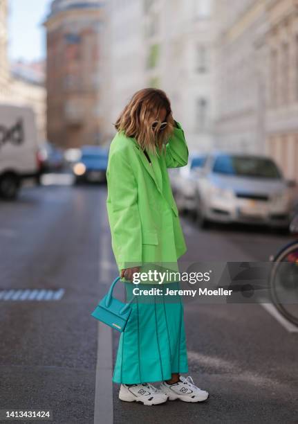 Karin Teigl wearing New Balance white and navy blue sneaker, Jacquemus neon green oversized blazer and Jacquemus colorful blue long skirt, Lumina...